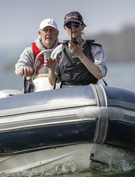 A volunteer driving a safety boat, with the crew at the front of the boat on a vhf radio