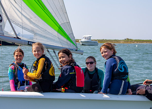 a group of smiling children on a sailing dinghy