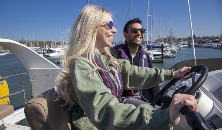 A man and a woman are sat at the helm of a boat.