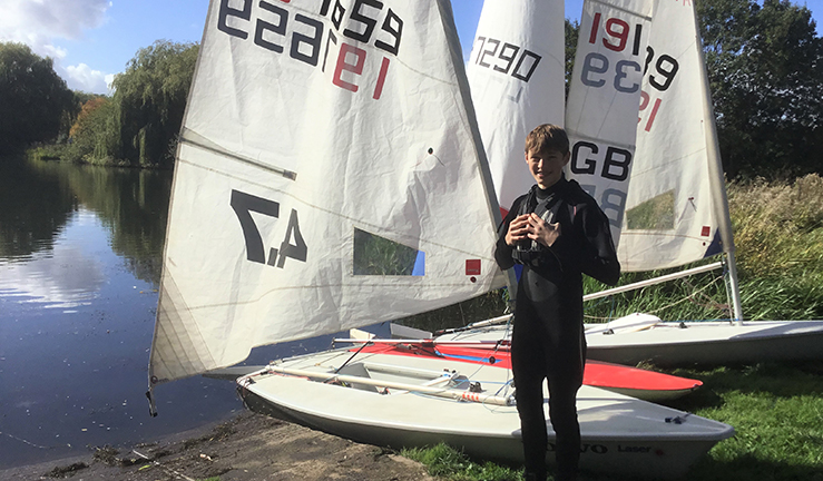 LRYSA youth sailor Edwin Jones by boats on shore.