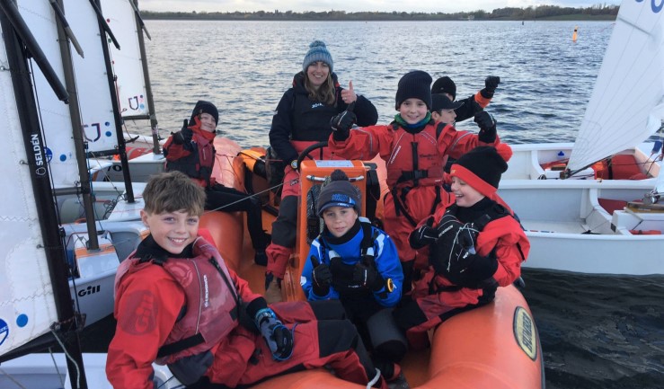 Optimist sailors gathered around their coach boat during an RYA Midlands Regional Training Group session at Draycote Water, 2021.
