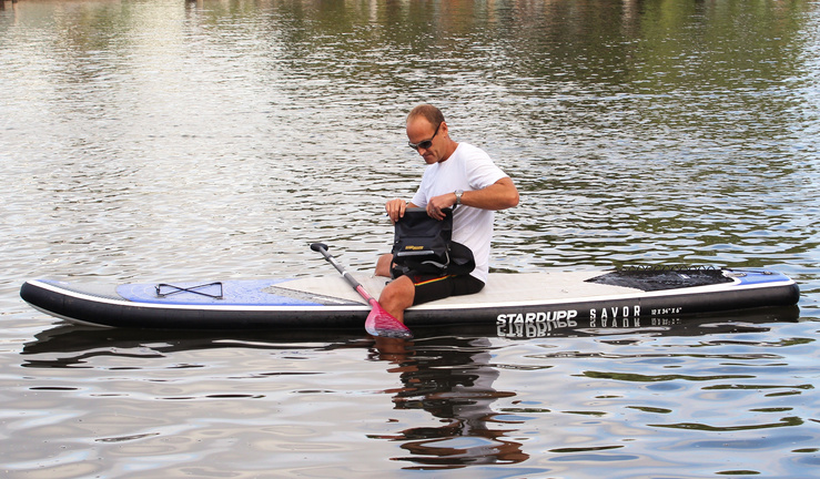 Man on paddle board with dry bag