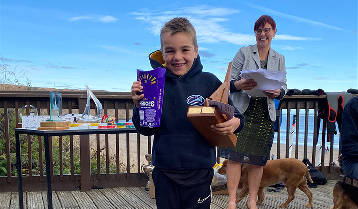 NEYYTS Regatta Fleet winner 2022 Harry Wilson at the prize giving with a box of chocolates and trophy and a big smile!