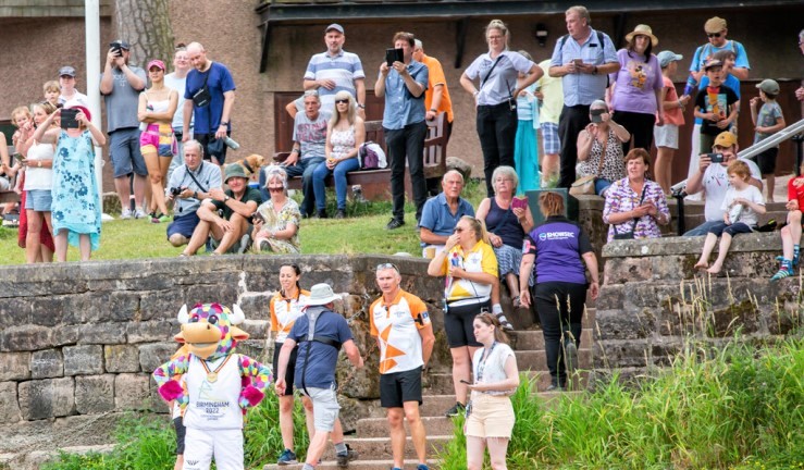 Crowds wait for the arrival of the Queen's Baton Relay via boat at Rudyard Lake along with Commonwealth Games mascot Perry.