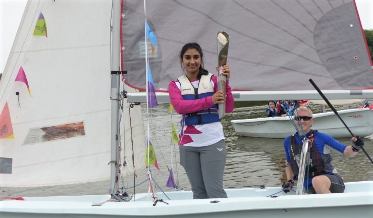 The Queen's Baton Relay being sailed across a lake in a Bahia by Tamworth SC members at Kingsbury Water Park, Warwickshire.