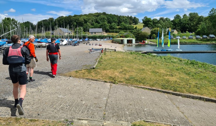 Instructors walking along the shore to some rigged boats on a pontoon.