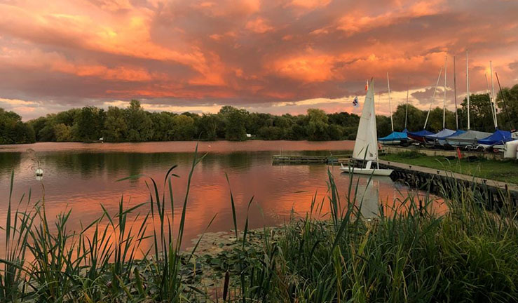 View of a boat returning to shore with a beautiful orange sunset after Syston SC's last Wednesday evening race of the 2022 season.