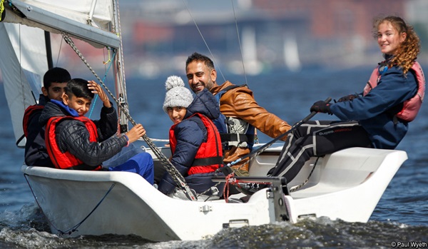 Group of people in keelboat waving at photographer