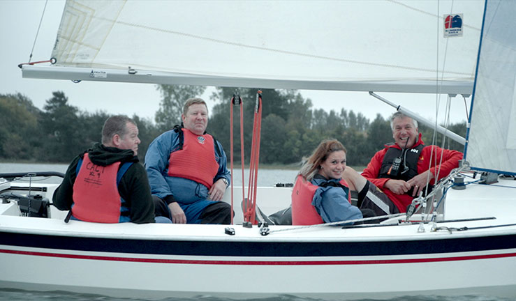 four sailors in a small keelboat out on the water