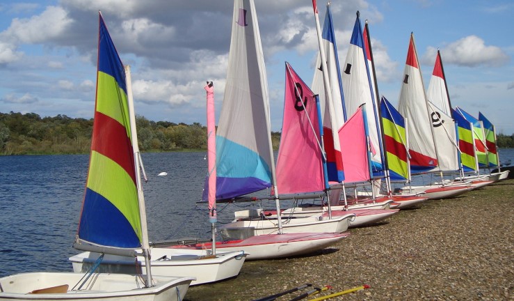row of junior dinghies on shore with sails up in the sunshine 