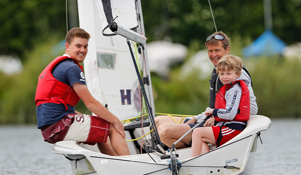 three generations are sailing in a dinghy