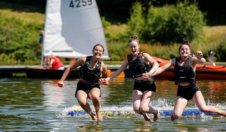 Wide shot of three teenagers jumping in the water