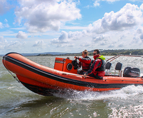 An image of an orange RIB underway on the water.