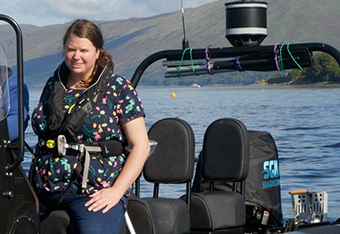 Hannah Earl-Payne, standing in a powerboat with hills in background