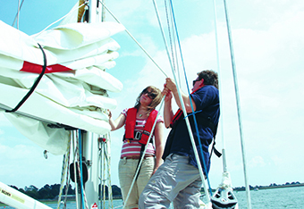 AN instructor by a mast of a cruising boat with a student.