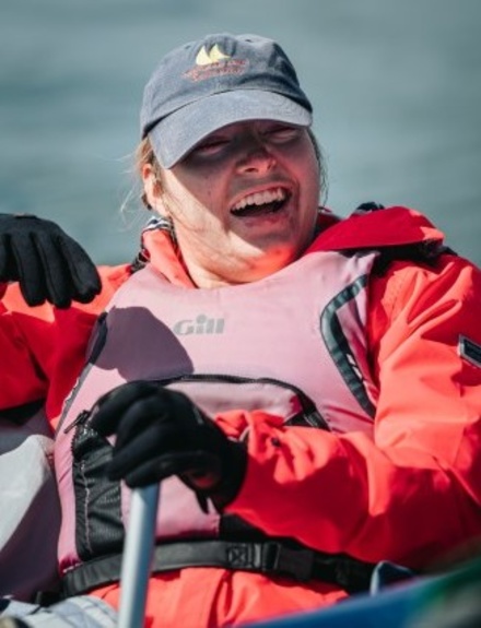 Disabled sailor smiling, steering a boat via a joystick