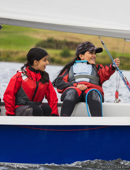Mother and daughter sailing in a dinghy smiling