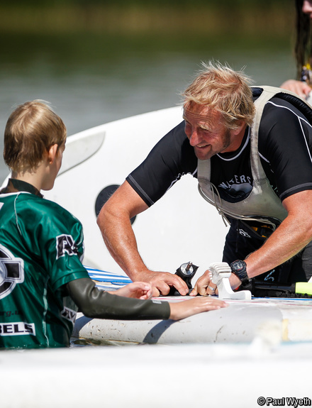 Instructor with child adjusting the fittings on a windsurfer