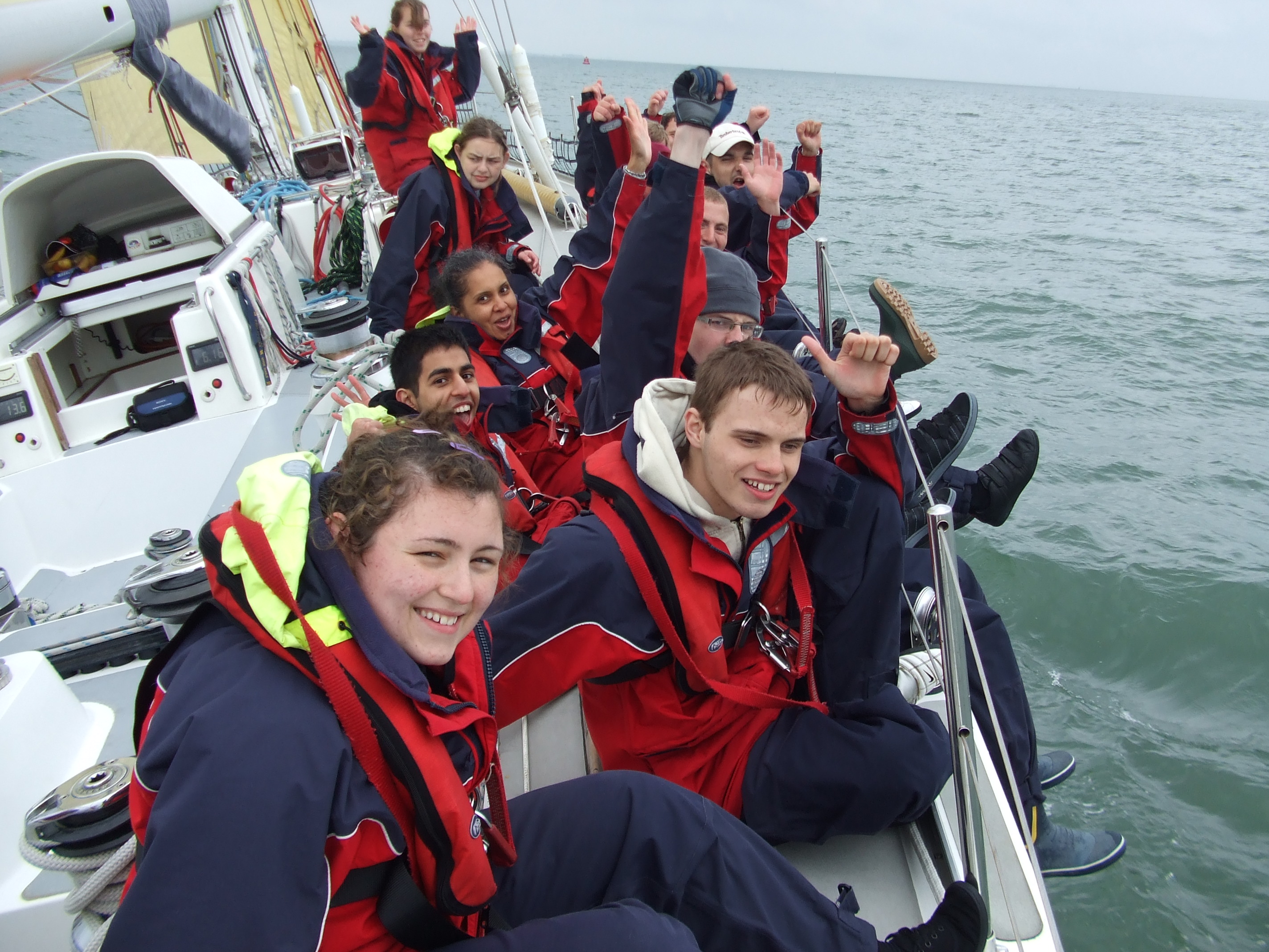 a group of young people enjoying a sailing adventure, all sitting on the side of the deck