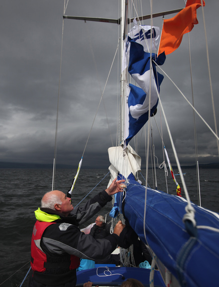 A Race official hoists flags onboard a committee vessel
