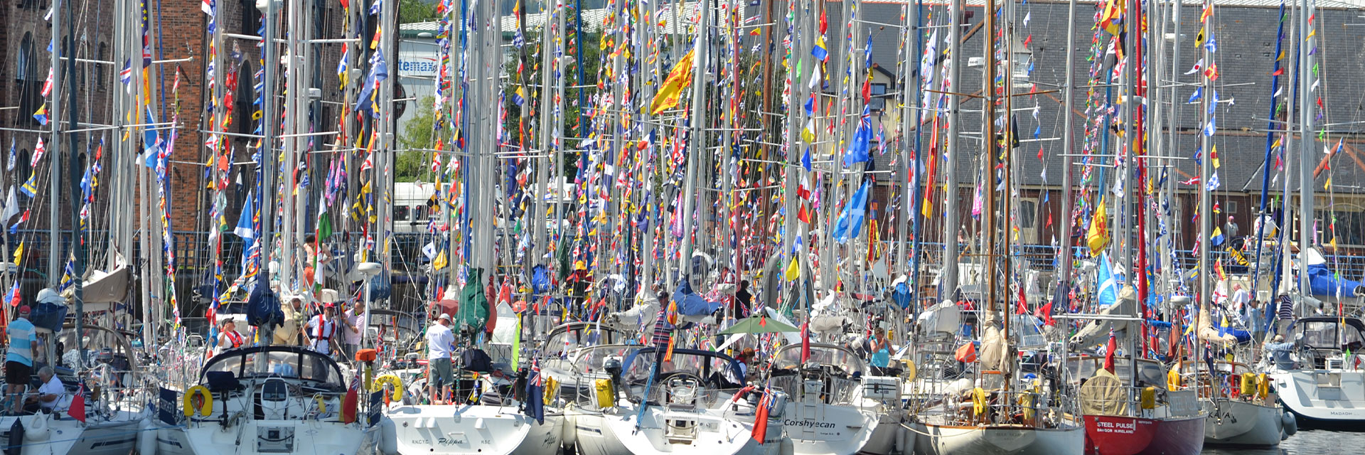 Many boats moored covered in colourful flags at the marina