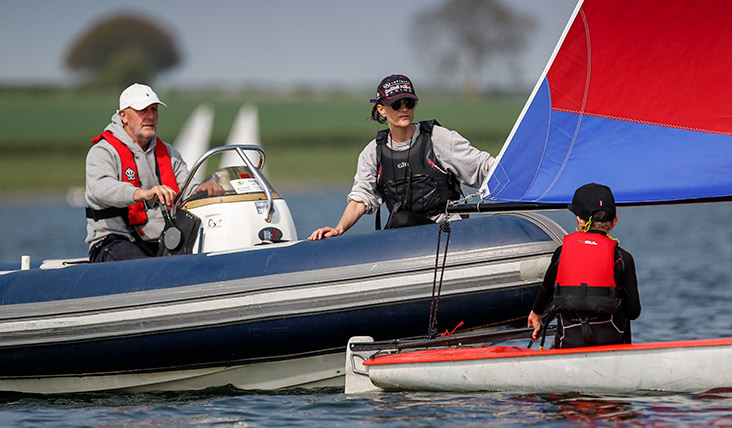 wide shot of coach teaching how to sail on the open water