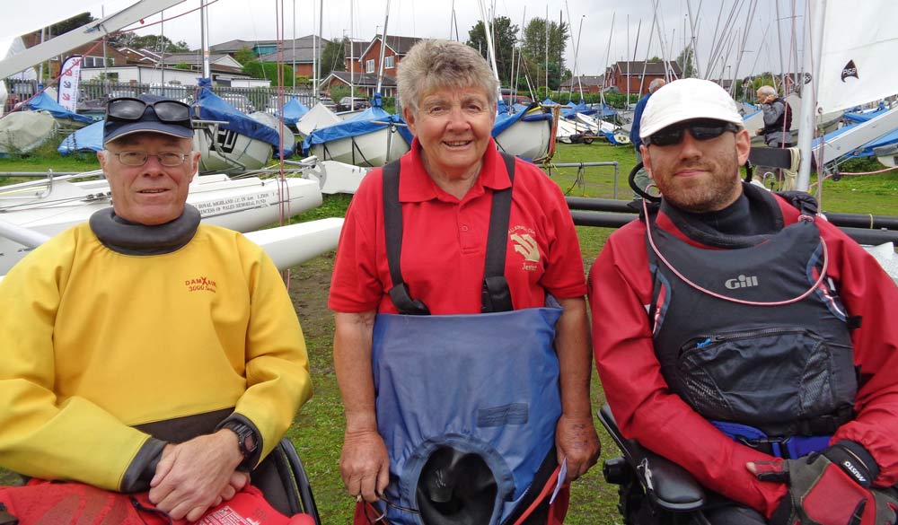 Three dinghy sailors stood next to eachother