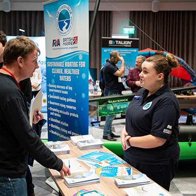 candid shot of an exhibitor talking to an attendee about the amazing things going on in sailing and training