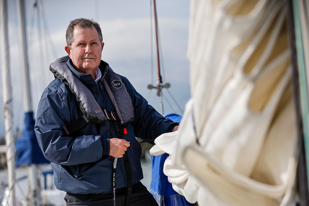 Mid shot of person standing in front of a boat in a habour