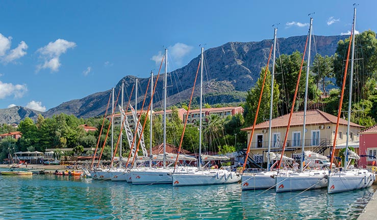 establishing shot of a fancy flotilla moored next a beautiful sunny European village 