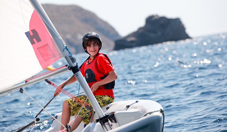 mid shot of smiling child sailing a dinghy 