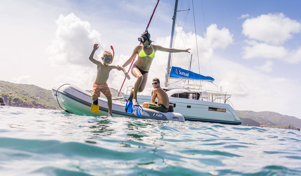 Sunsail family jumping from dinghy into sea with snorkeling gear