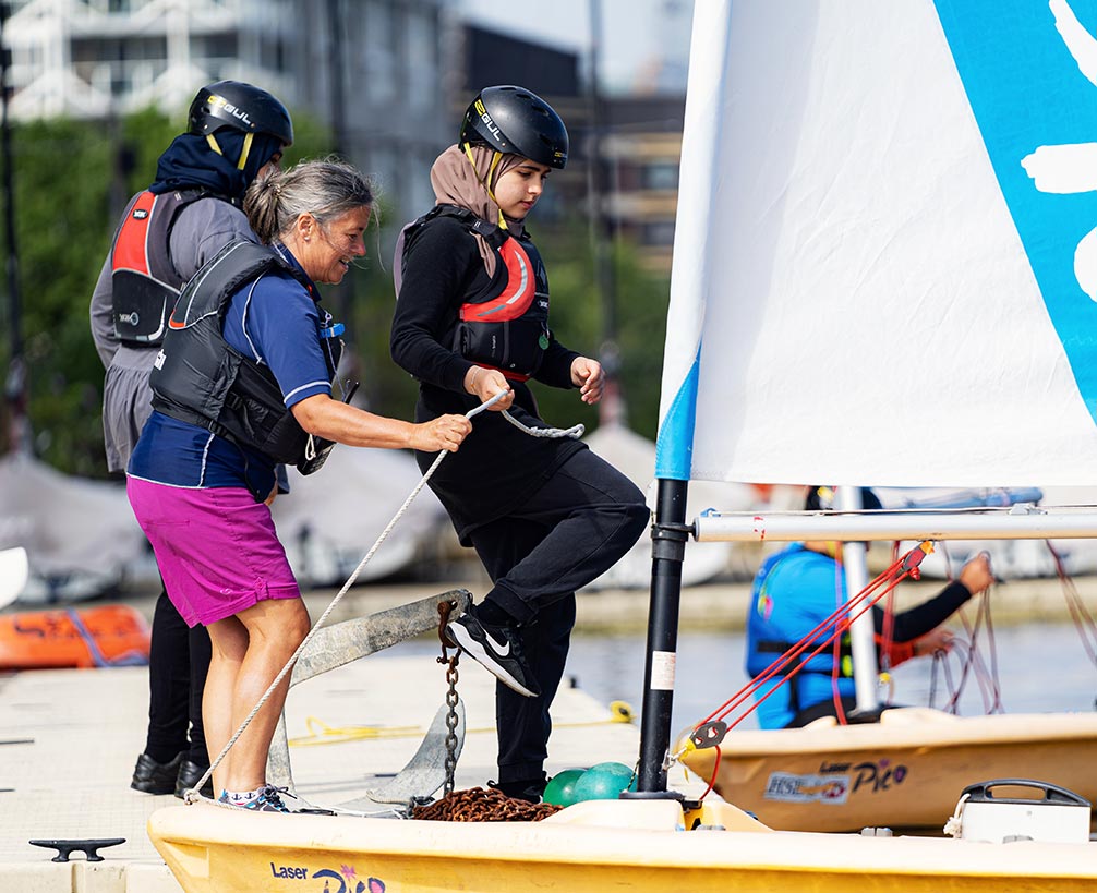 candid shot of a sea cadet climbing into a  sailing dinghy 