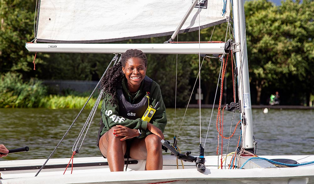 smiling shot of Rosa sitting in sailing dinghy on a lake 