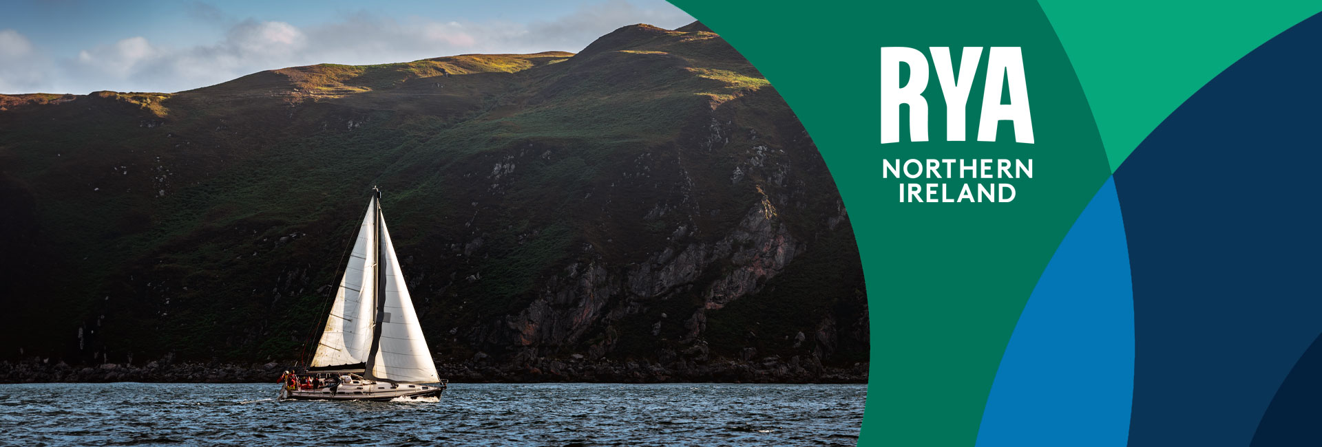 RYA Northern Ireland hero - sailing boat in front of a cliff face 