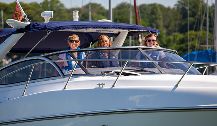three women posing for a picture while driving a motorboat