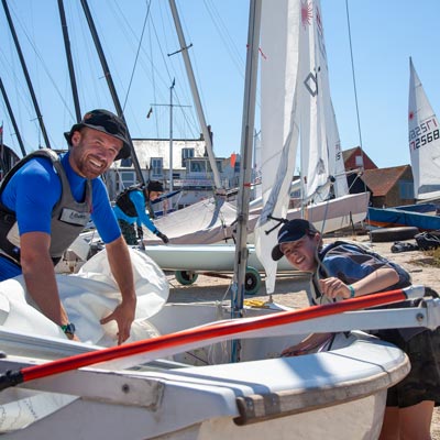 a father and son preparing a sailing dinghy to go out on a sunny day