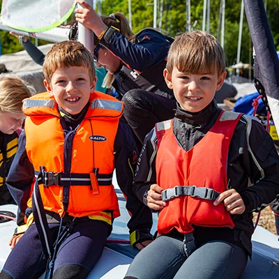 two kids wearing life preservers waiting to go sailing