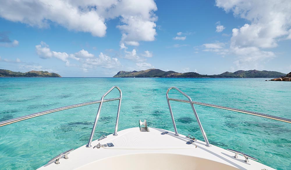 Bow of ship at sea with turquoise water between tropical islands on sunny day. Praslin Island, Seychelles.