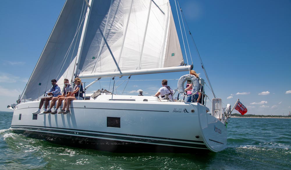 Yacht sailing on sunny day with crew on high side