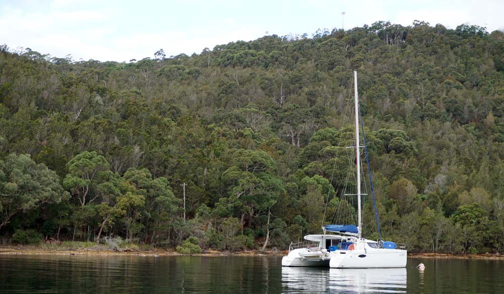 wide shot of boat floating on the coat with hills and trees in the distance 
