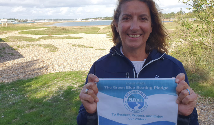 Wide shot of woman holding a Green Blue boating pledge certificate