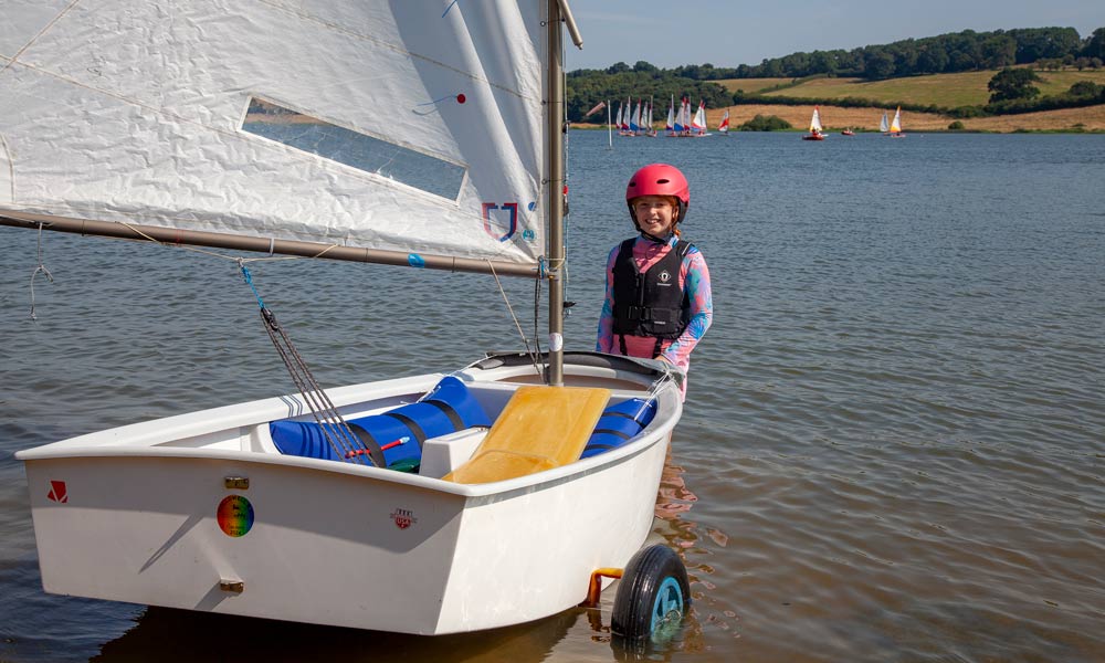 Child stood next to their dinghy 
