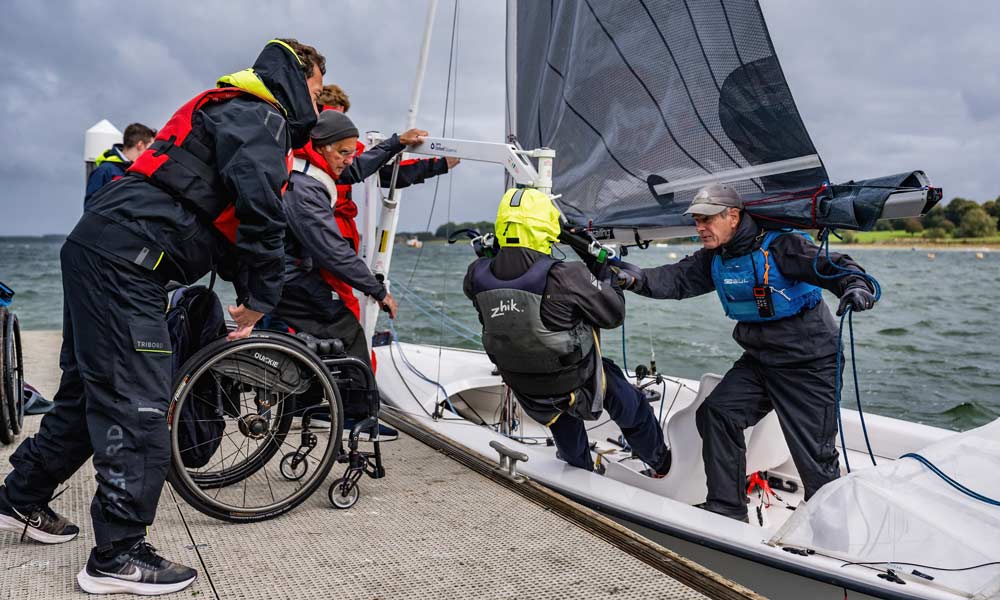man in wheelchair being helped onto boat