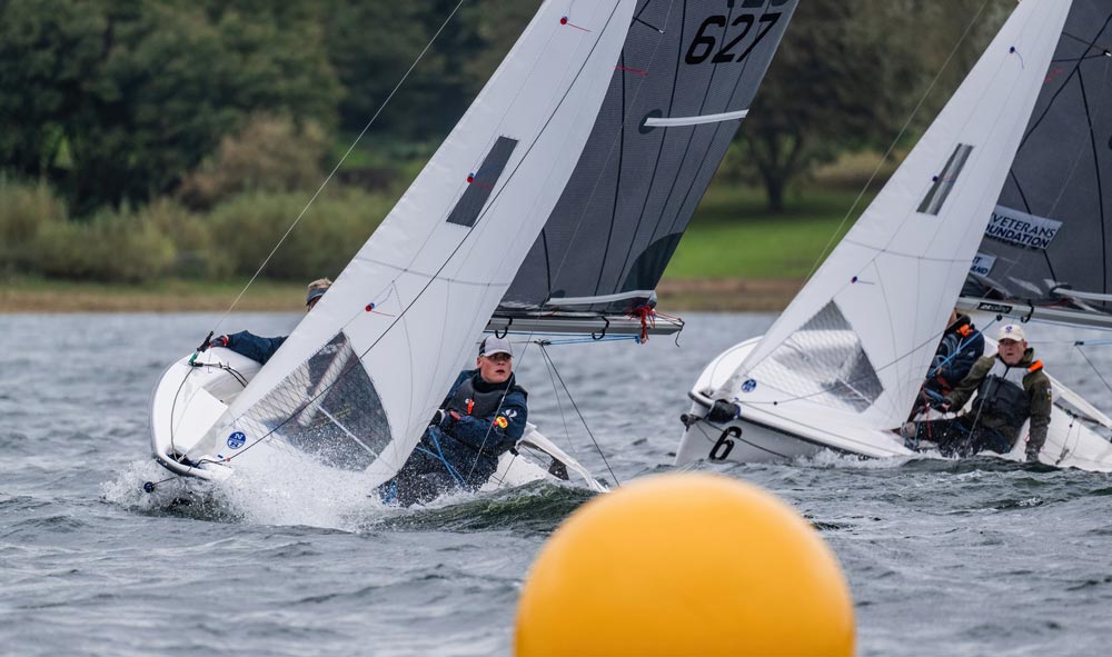 two boats sailing near a yellow buoy 