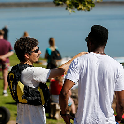mid shot of two people talking about sailing next to a lake