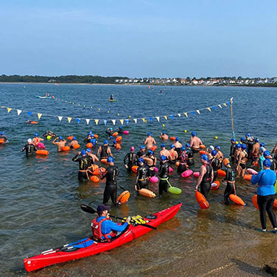 wide shot of a crowd of participants taking part in open water swimming in a lake