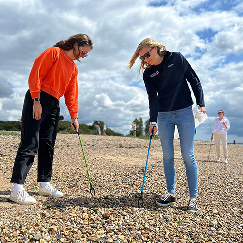 posed shot of two people litter picking on beach