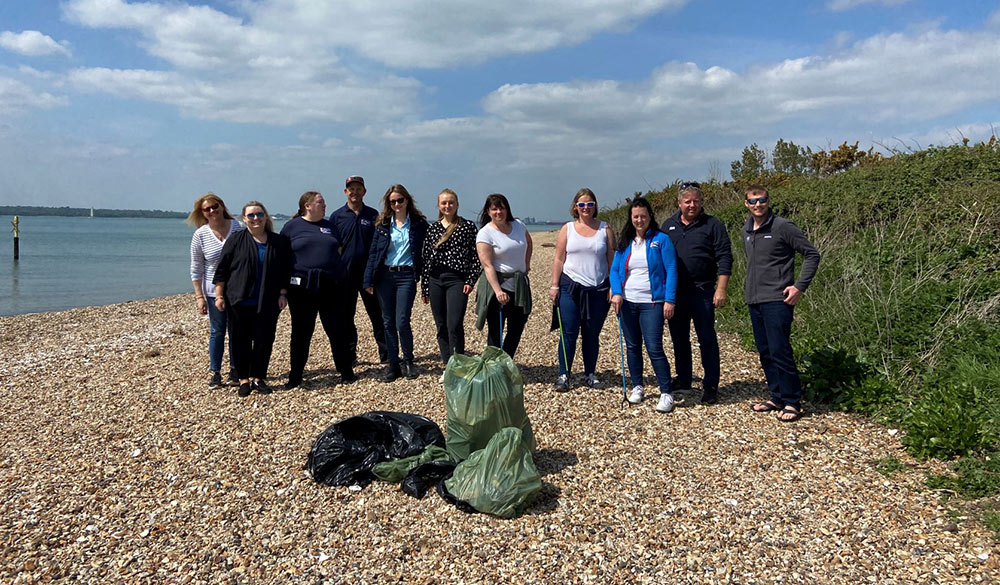 wide shot of a group of litter pickers on the beach after collecting lots of rubbish  