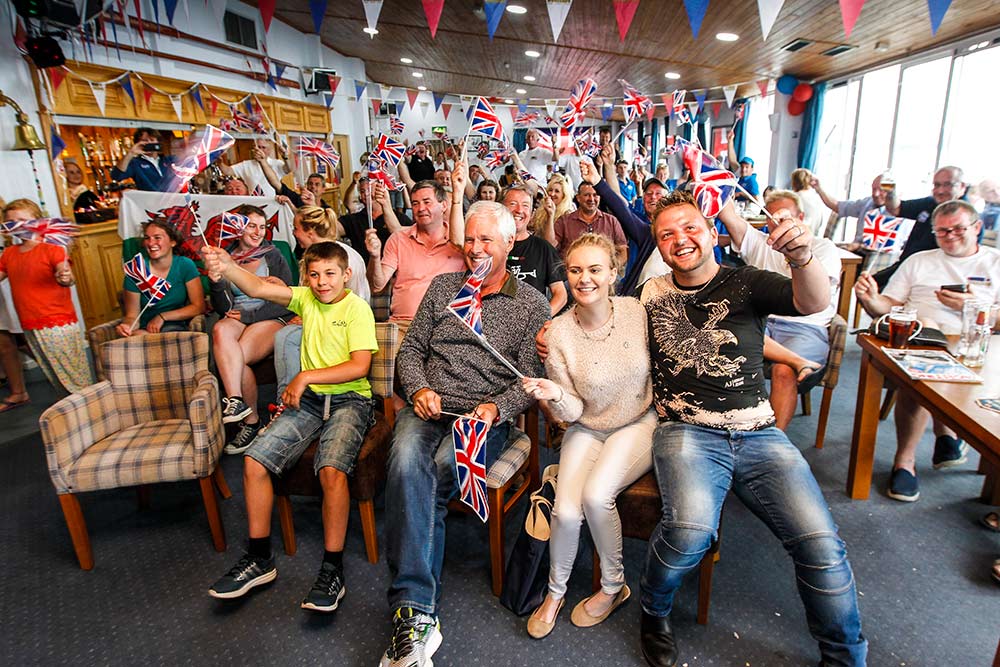 people celebrating while watching the Olympics on tv a in a sailing club